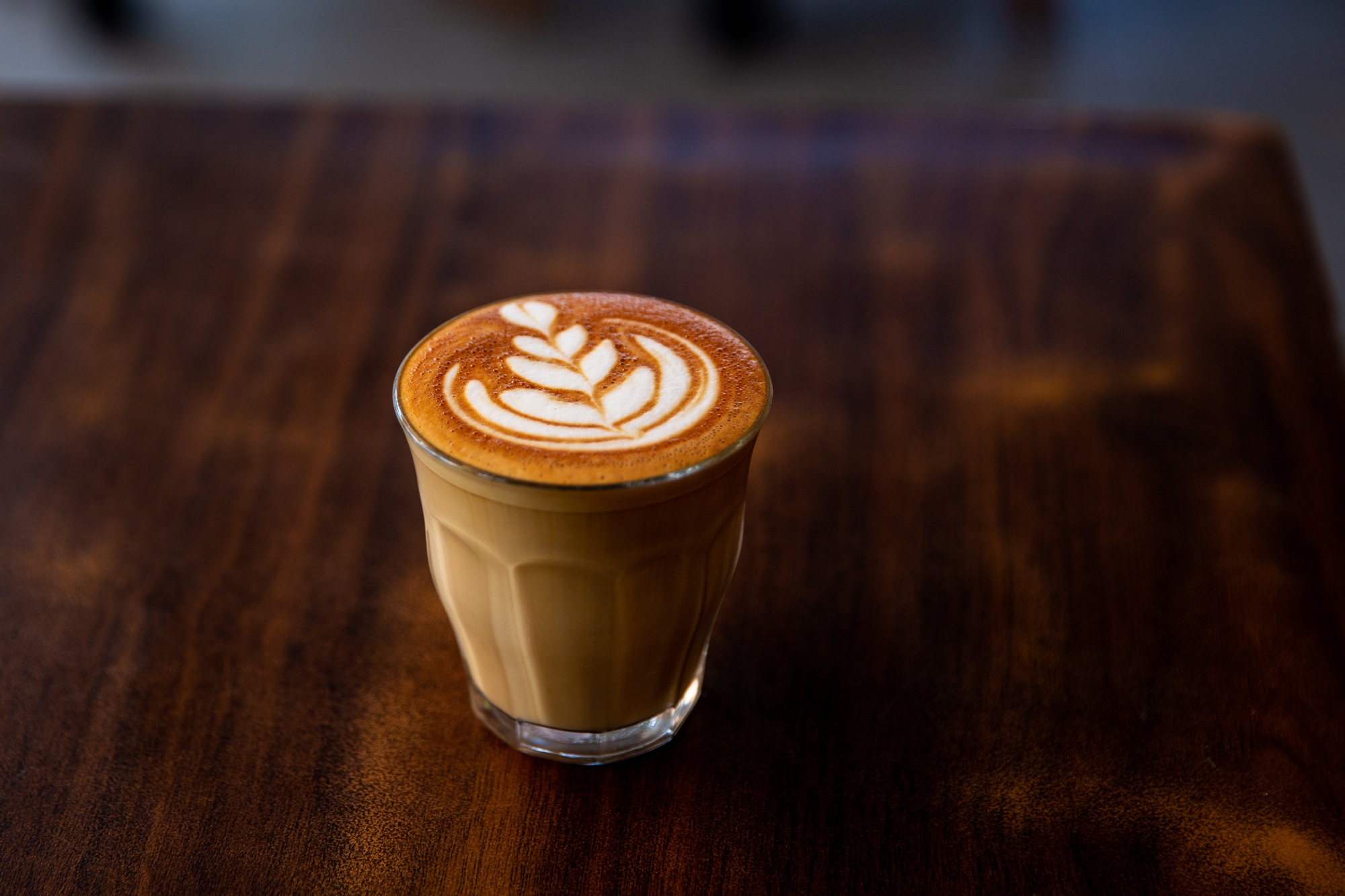 Glass of flat white coffee with heart shaped foam milk